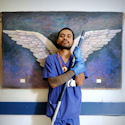 Zito Soares Da Silva with painted wings on a wall behind, angel-like