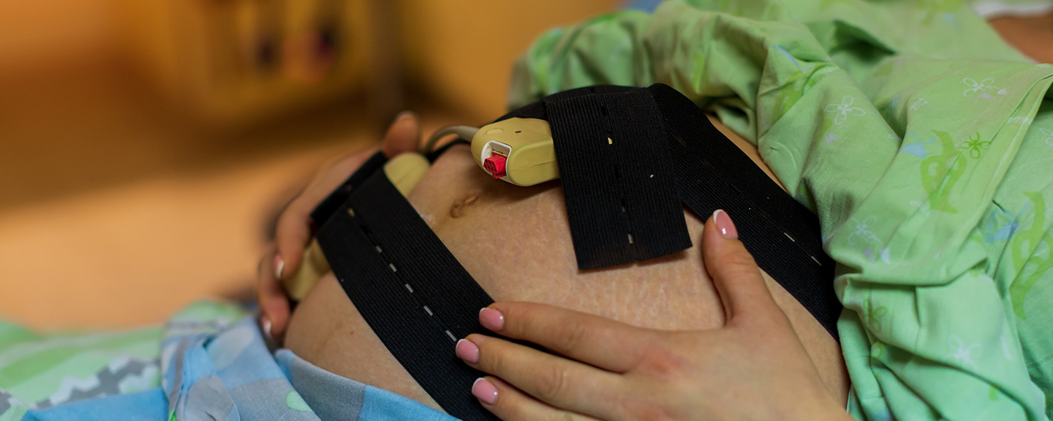 Close-up of monitor strapped around pregnant woman's 'bump'