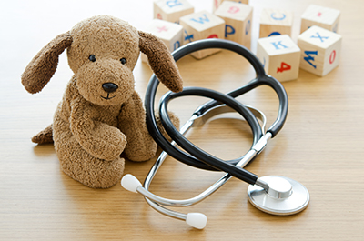 Cuddly dog, stethoscope and toy wooden blocks on a desk surface