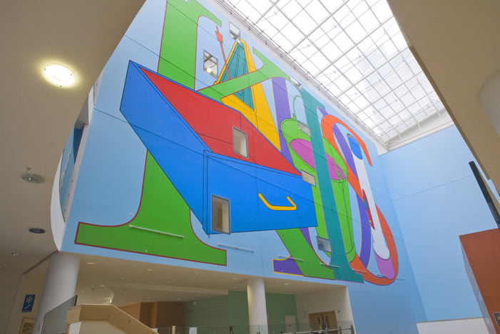 Huge naive painting of decorated word 'KIDS' on a high internal wall of an atrium