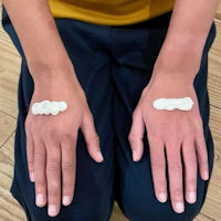Kneeling child's hands rest on their knees: a liberal smear of cream crosses the back of each hand