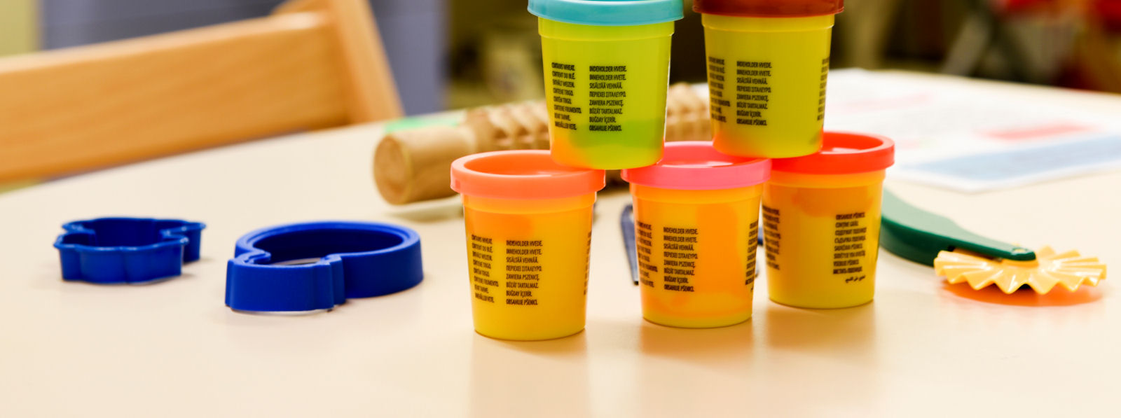 A stack of five play-do tubs with two cutters and a cutting tool
