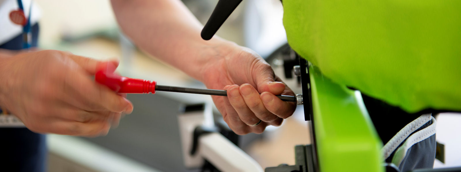 Close up of hands adjusting a piece of equipment with a tool