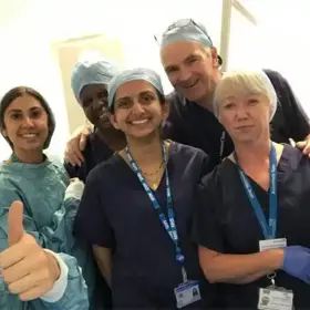Group of smiling clinicians, one giving thumbs up