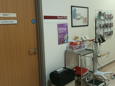 Clinic door with bin, trolley, wall map and leaflet rack in corridor