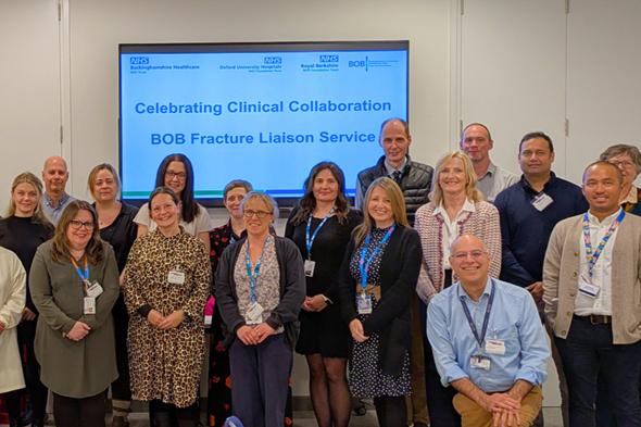 Group of NHS staff standing together in front of a presentation slide celebrating the BOB Fracture Liaison Service