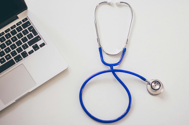 A stethoscope next to a laptop