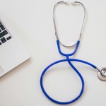 A stethoscope next to a laptop