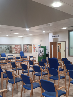 Well-lit waiting area with high ceiling, neat rows of modern chairs and large artworks on wall
