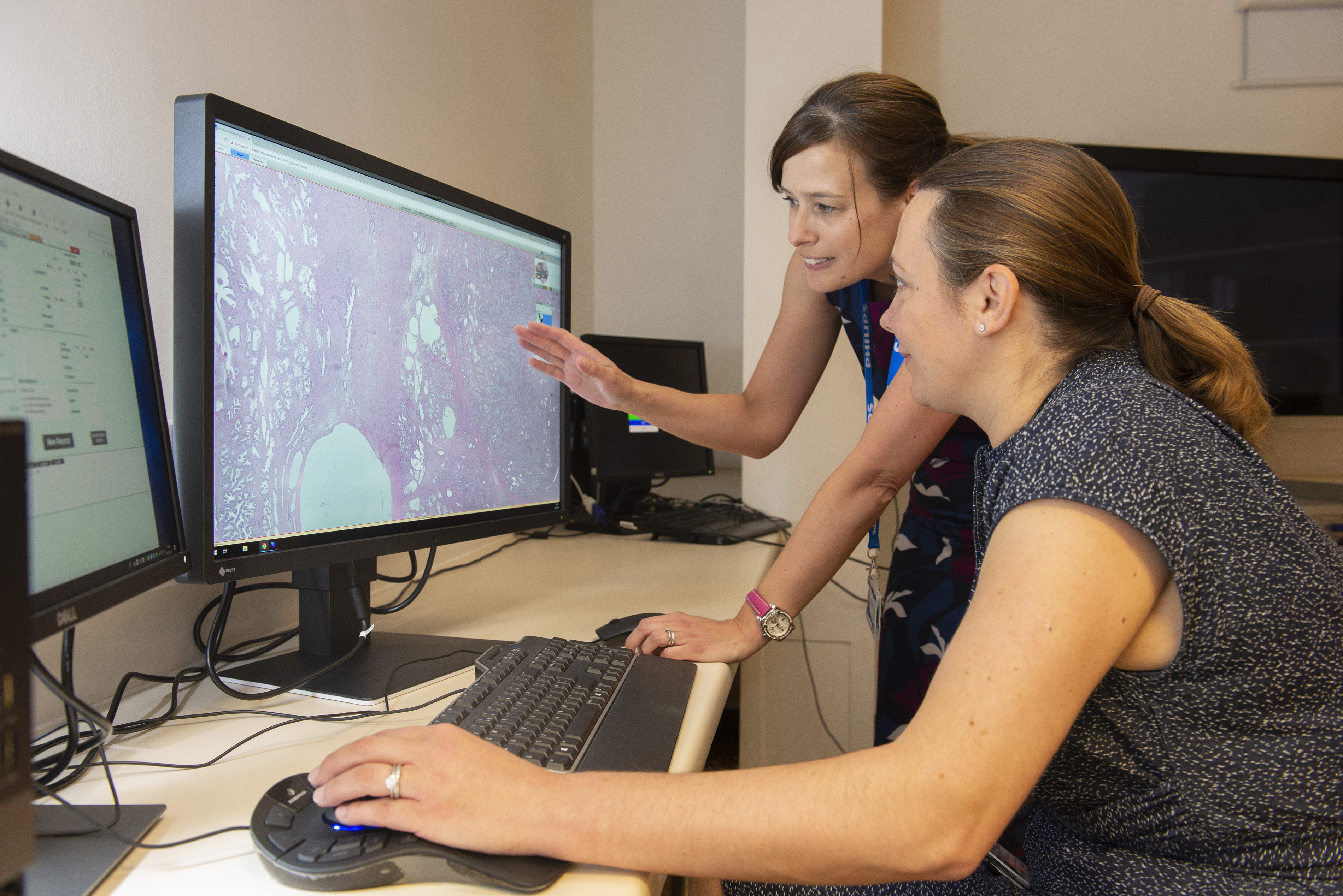Two women look at a digital pathology image on a screen