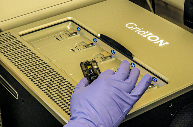 A gloved hand resting on a GridION machine