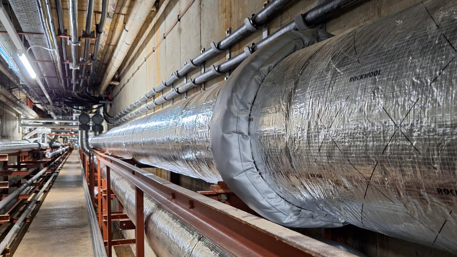 Large insulated hot water pipe in a service corridor.