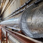 Large insulated hot water pipe in a service corridor.