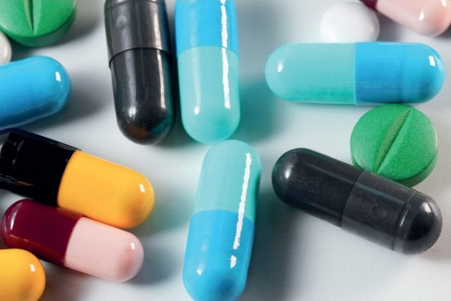 Around 10 pharmaceutical capsules and tablets on flat surface