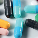 Around 10 pharmaceutical capsules and tablets on flat surface