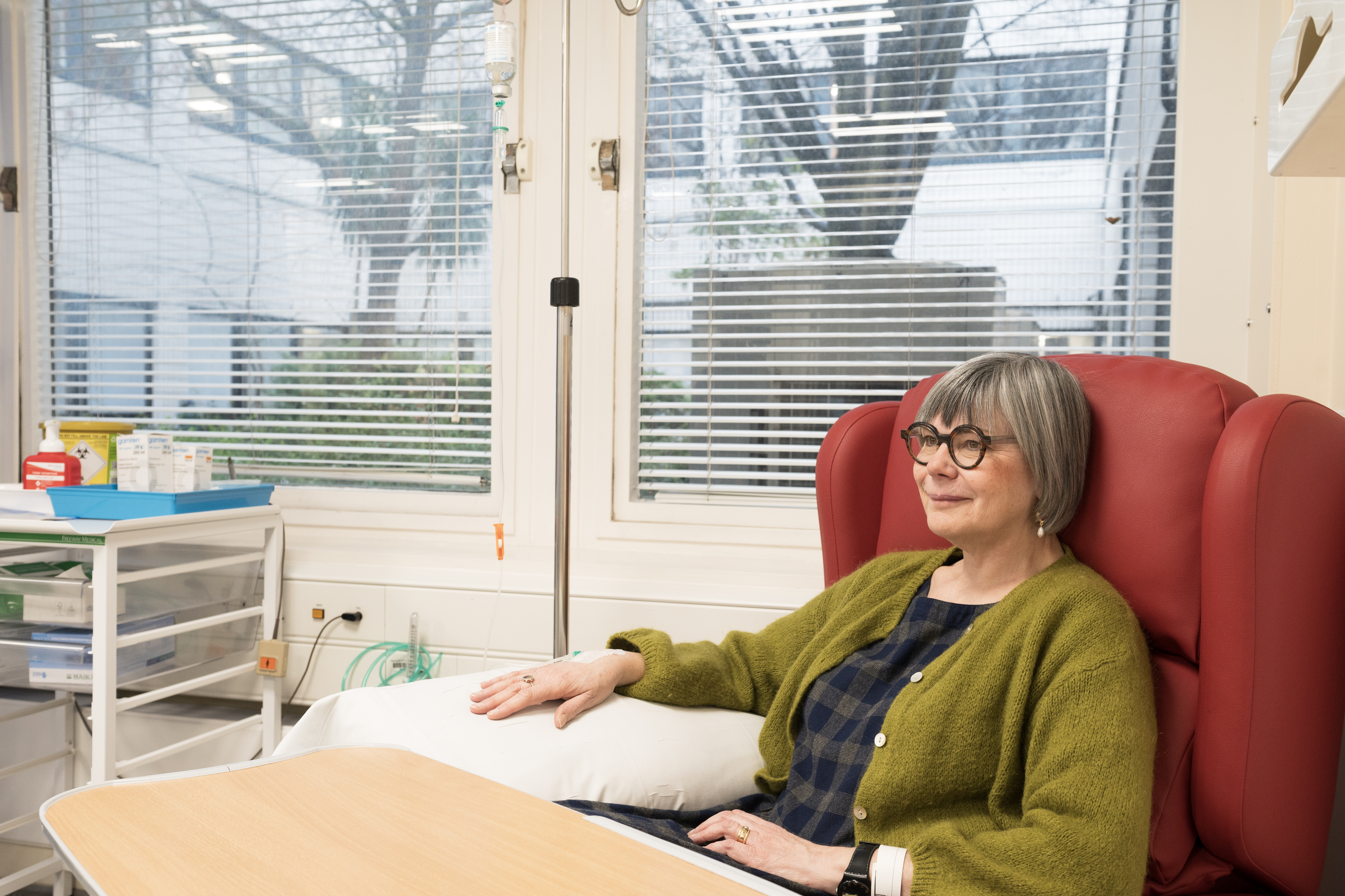 Person receiving an intravenous infusion while seated in a hospital treatment chair