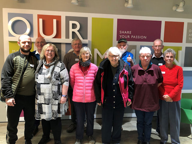 Eight people standing in front of a bright mural