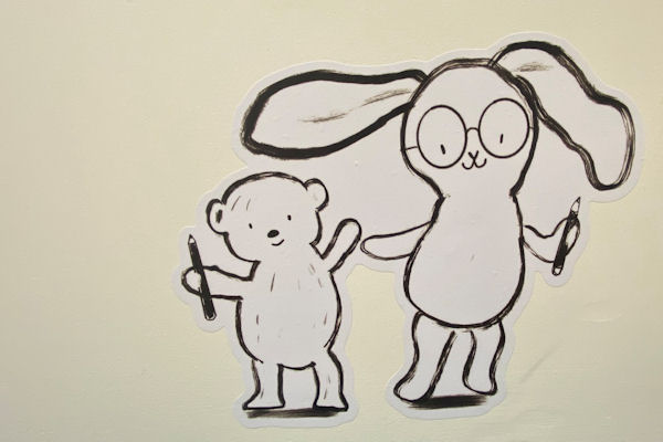 Line drawn cartoon of small teddy and larger bunny in glasses, both holding pens.