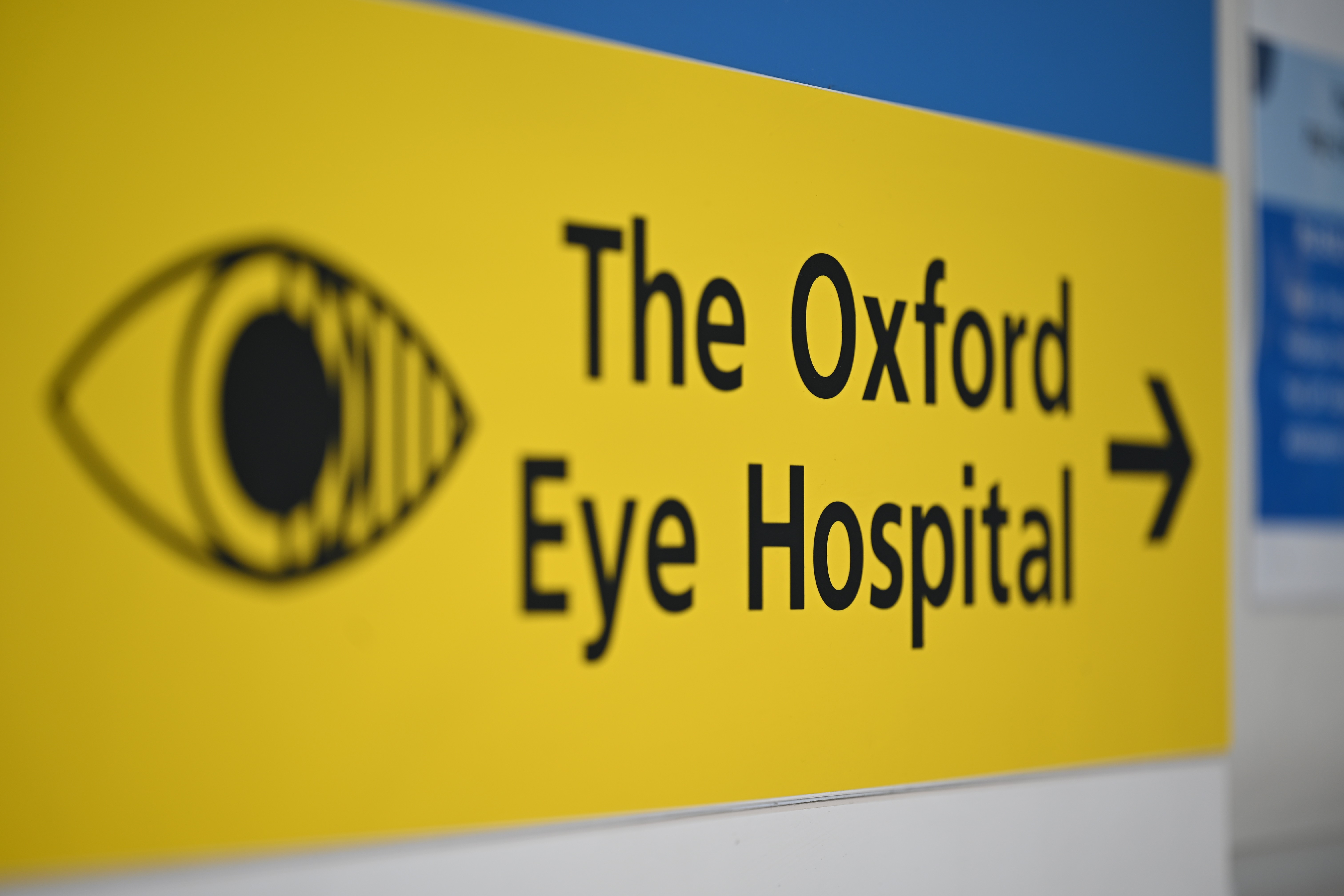 Black text on a yellow sign that reads: "The Oxford Eye Hospital". There is an image of an eye to the left and an arrow pointing right on the right