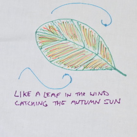 Pen drawing of an autumn leaf with the text 'Like a leaf in the wind catching the autumn sun'.