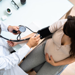 doctor measuring blood pressure of pregnant woman 