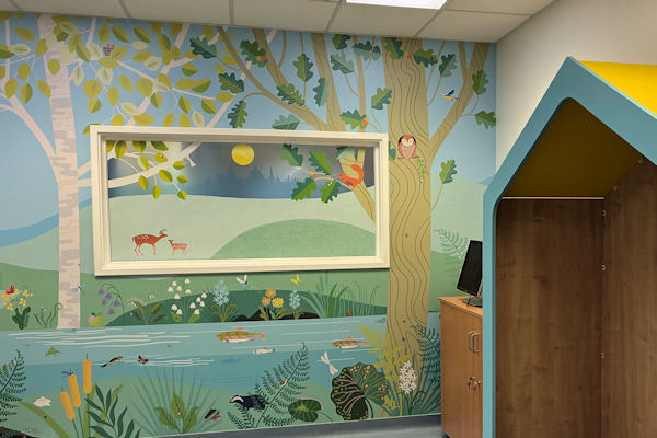 Interior wall with mock window frame, painted with trees, owl and deer.