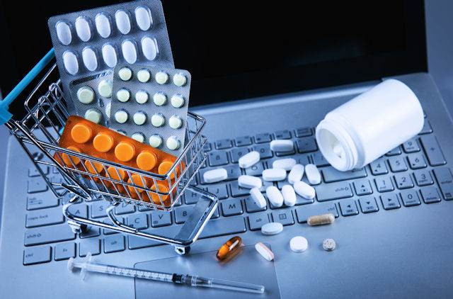 Pharmaceutical pills and a syringe on a laptop keyboard