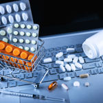 Pharmaceutical pills and a syringe on a laptop keyboard
