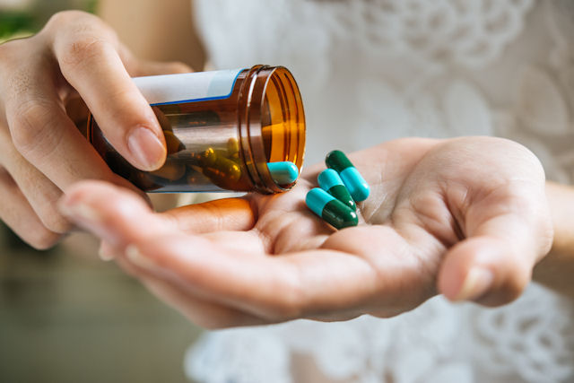 Hands tipping pills from a container