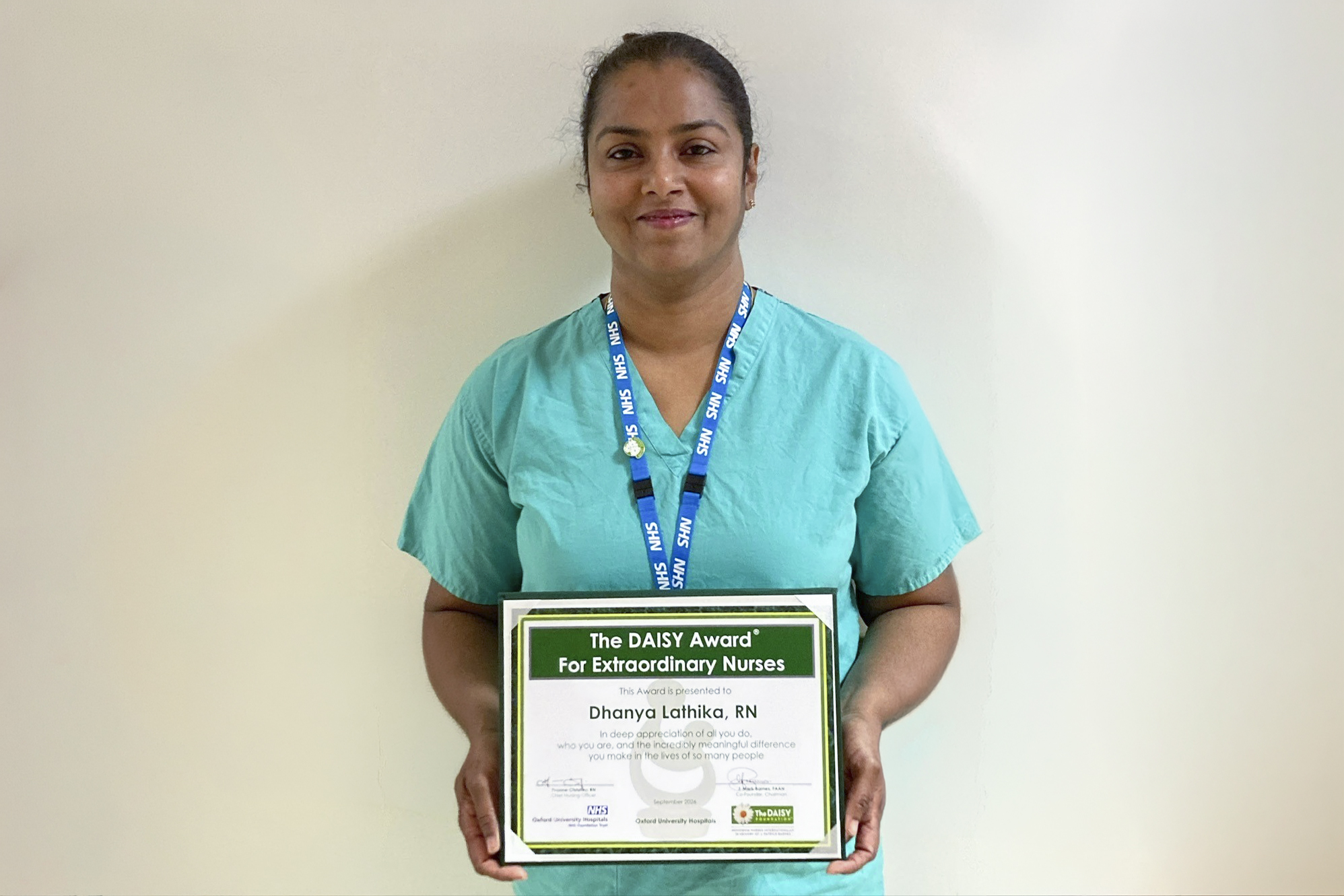 Person holding a DAISY Award certificate while wearing theatre scrubs