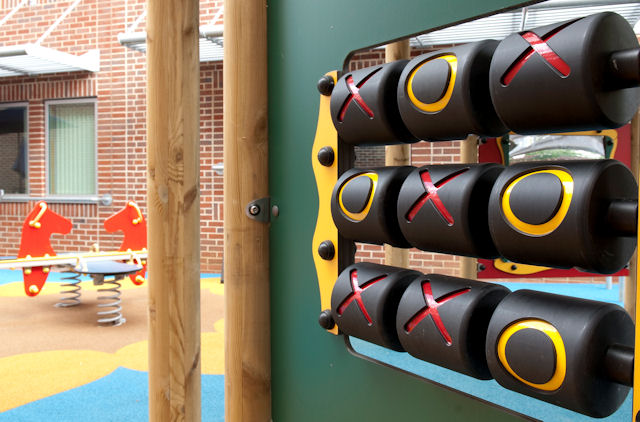 A giant noughts and crosses game in a play park with rocking horses behind