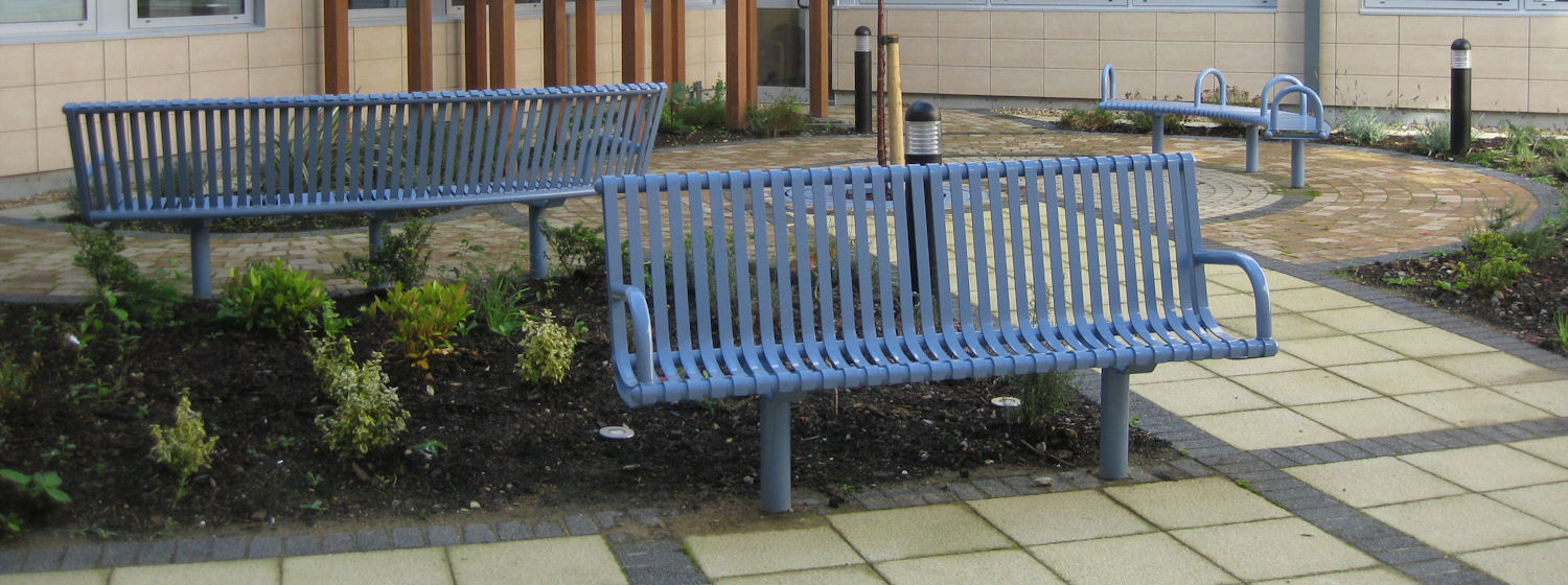 Two metal benches in a garden at the Churchill Hospital