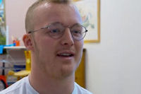 Young man with cropped hair and round glasses in bright clinic room