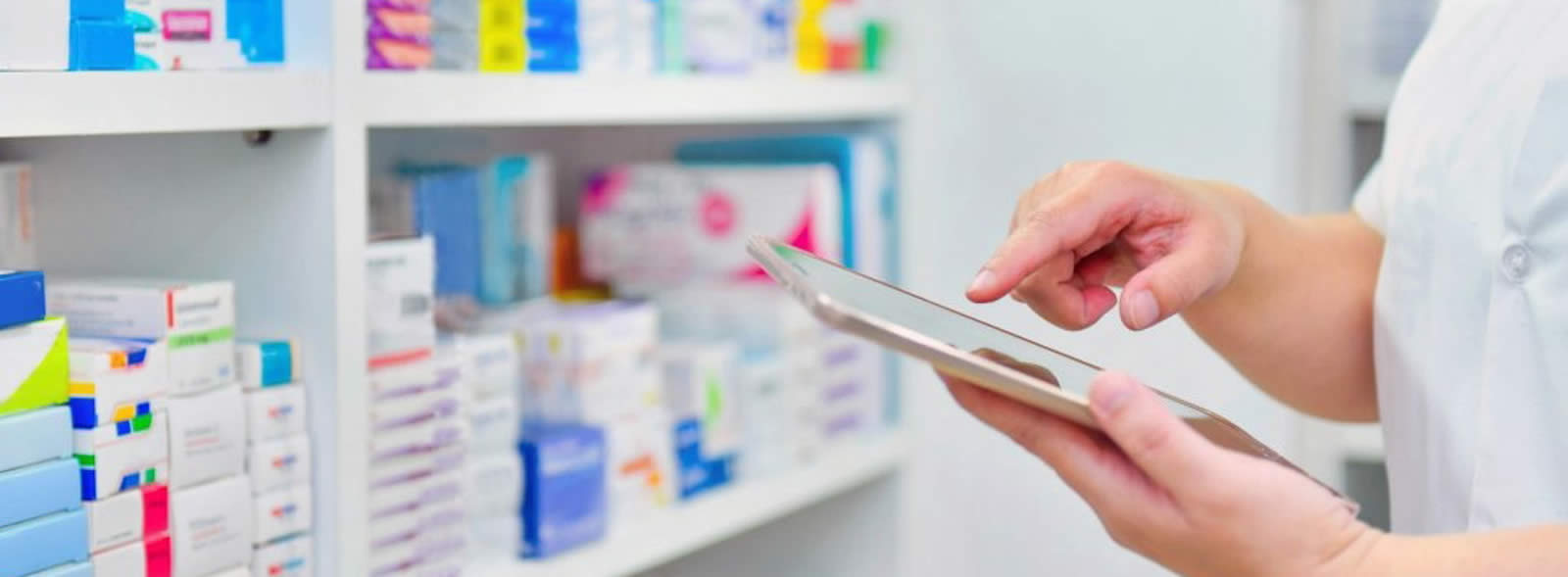 Shelves of medicines, hands holding tablet